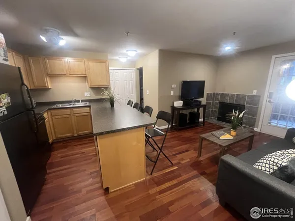 a kitchen with stainless steel appliances granite countertop a stove top oven a sink dishwasher a dining table and chairs with wooden floor