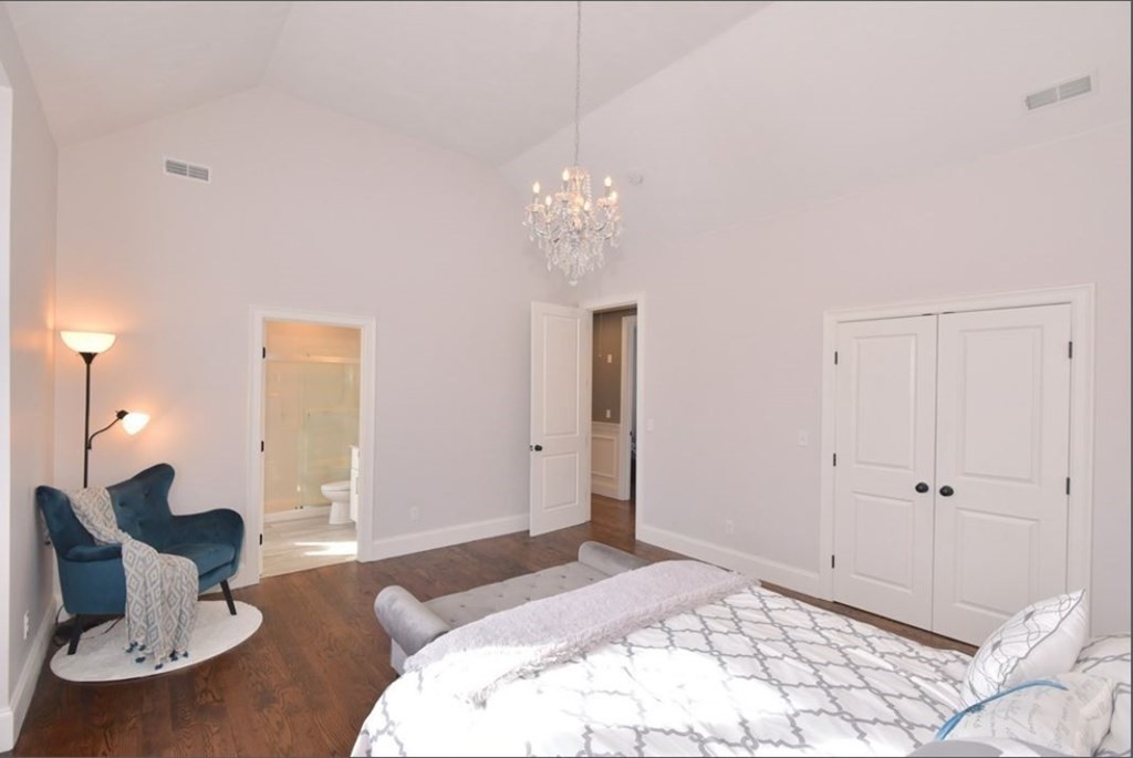 261 Main Street, Unit 1 Shrewsbury, MA 01545 - Photo 7 of 14 a spacious bedroom with a bed and a chandelier