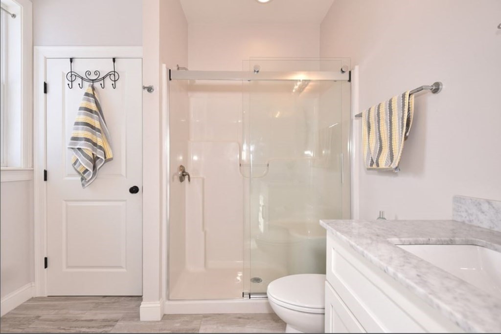 261 Main Street, Unit 1 Shrewsbury, MA 01545 - Photo 8 of 14 a bathroom with a granite countertop sink toilet and shower