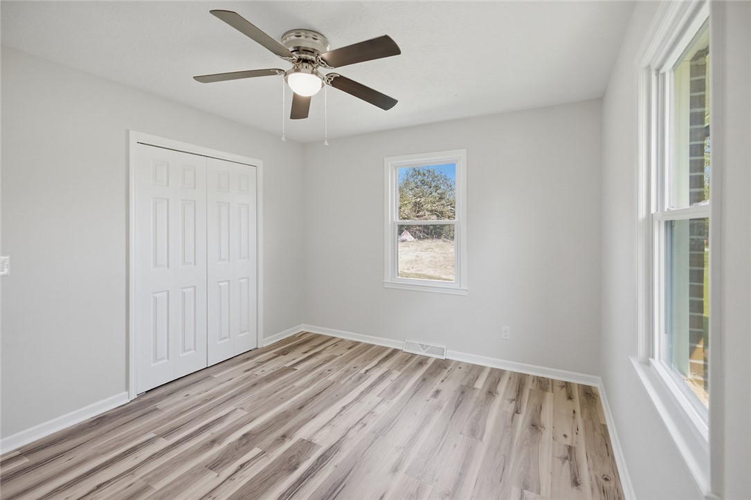 902 Cherokee Road Pelzer, SC 29669 - Photo 2 of 38 A well-lit bedroom with modern wood-look flooring and a functional ceiling fan.
