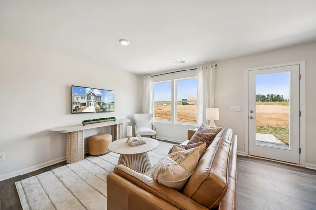 a living room with furniture a wooden floor and next to a window