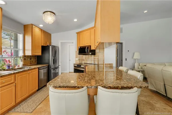 a kitchen with stainless steel appliances granite countertop a sink a stove and a refrigerator