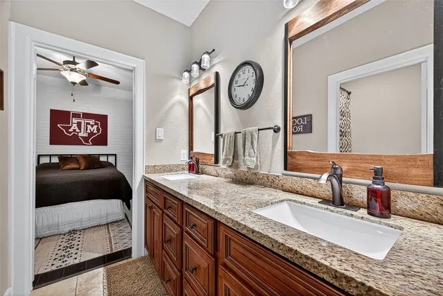 a en suite bathroom with a granite countertop sink and a mirror