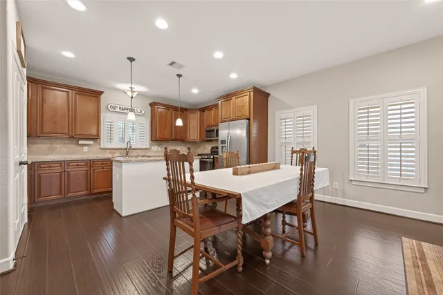 a kitchen with a table chairs a sink dishwasher a refrigerator and cabinets with wooden floor