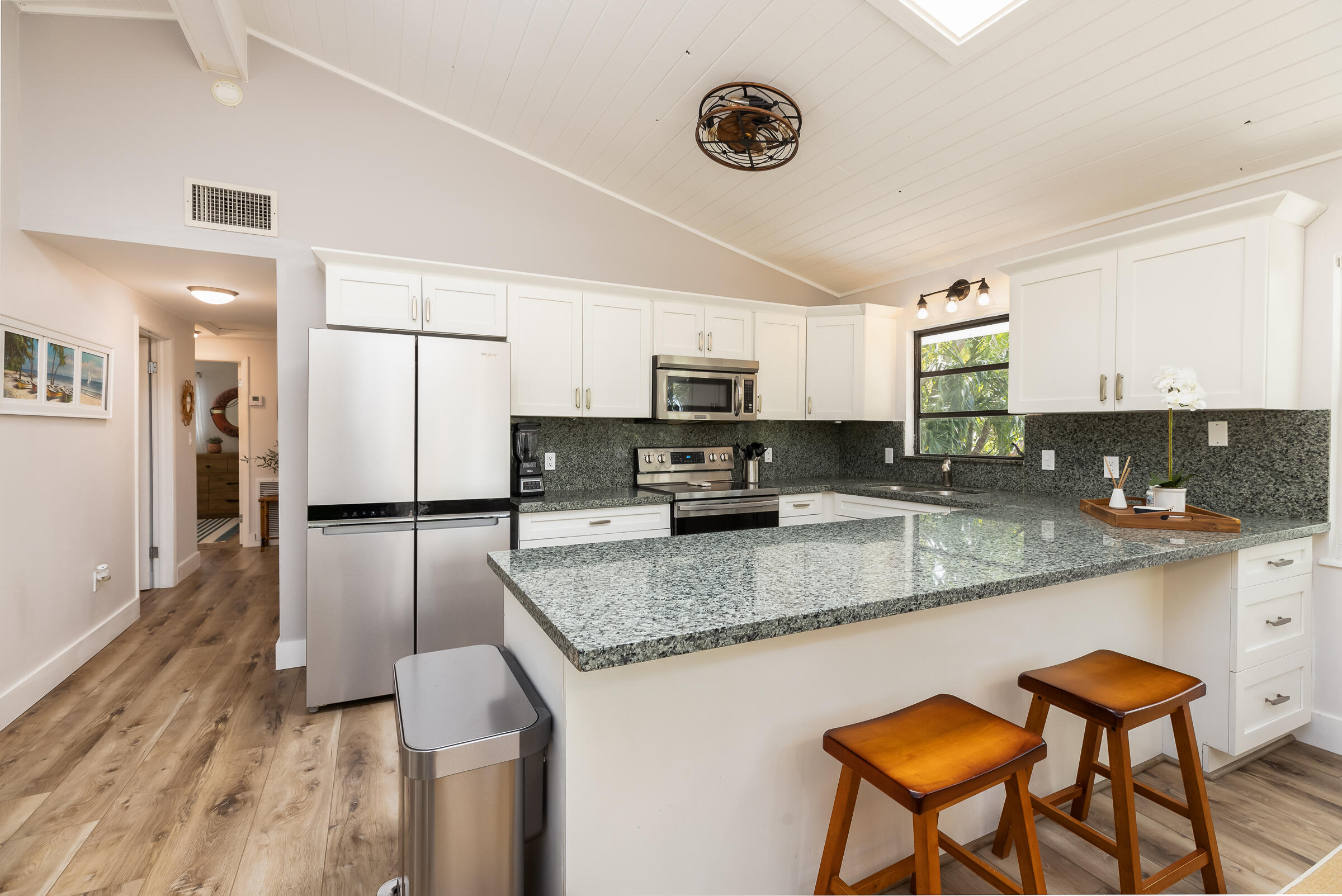 15 Sunset Road Key Largo, FL 33037 - Photo 16 of 58 a kitchen with stainless steel appliances granite countertop a stove top oven a sink a refrigerator white cabinets and wooden floor