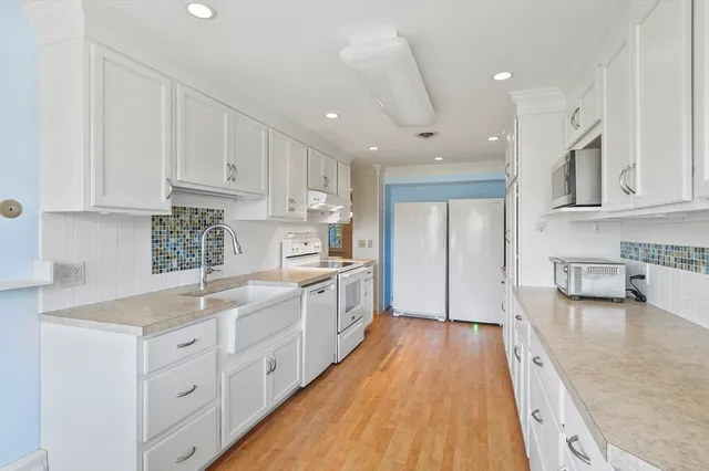 a large kitchen with stainless steel appliances granite countertop a lot of white cabinets and wooden floor