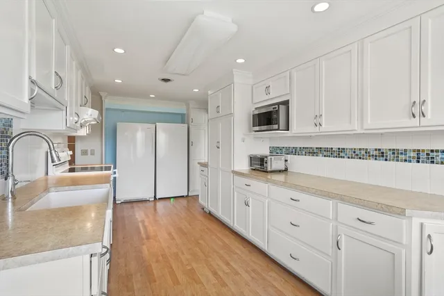 a large kitchen with granite countertop a sink and white cabinets