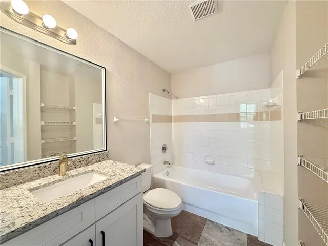 a bathroom with a granite countertop sink toilet mirror and bathtub