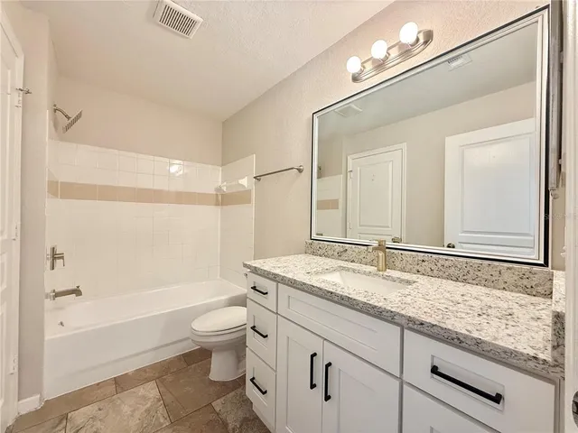 a bathroom with a granite countertop sink a toilet a mirror and shower