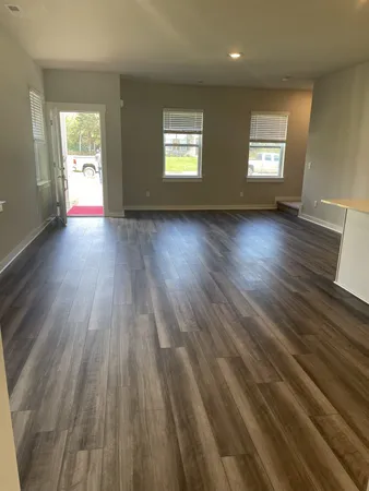 a view of an empty room and wooden floor and window