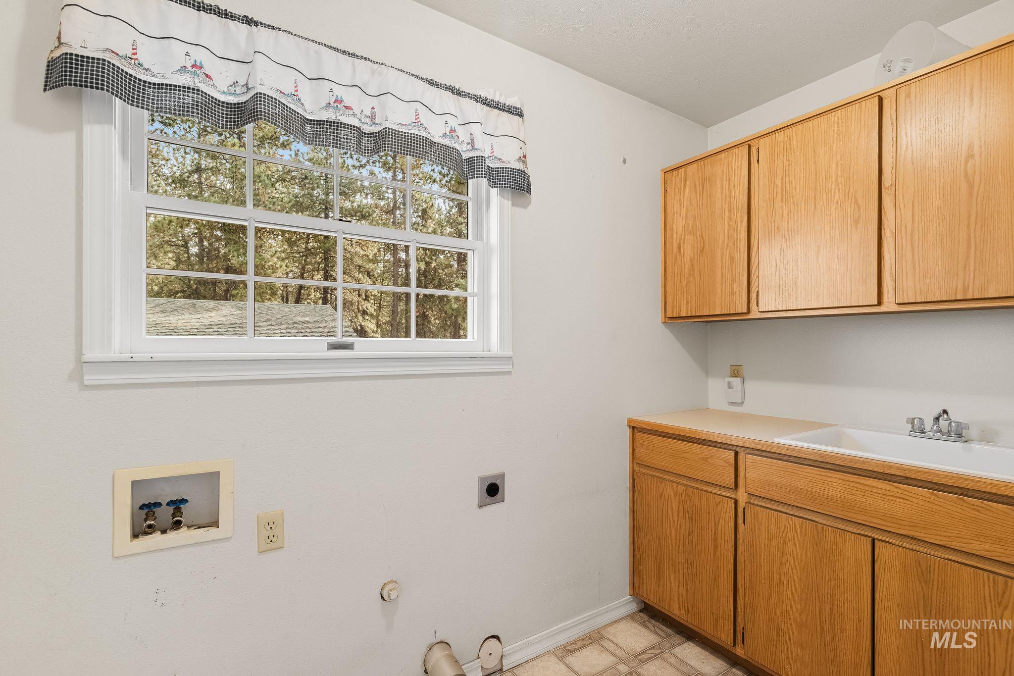 1820 Winchester Road Winchester, ID 83555 - Photo 16 of 50 Bright window, wood cabinetry, built-in sink, and laundry hookups