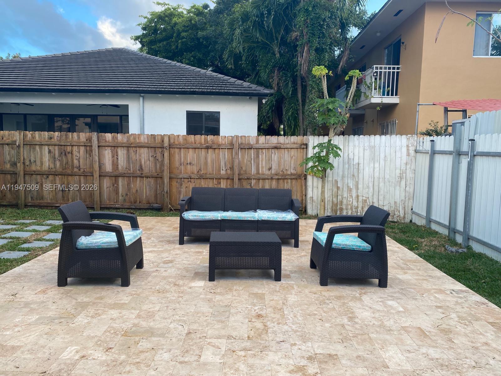 a view of a patio with couches chairs and wooden fence