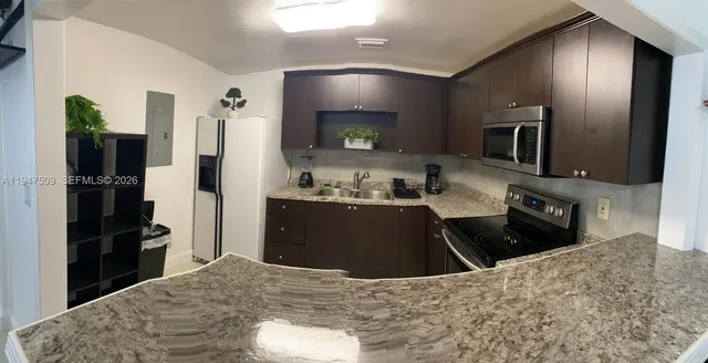 a kitchen with kitchen island granite countertop a refrigerator stove and sink