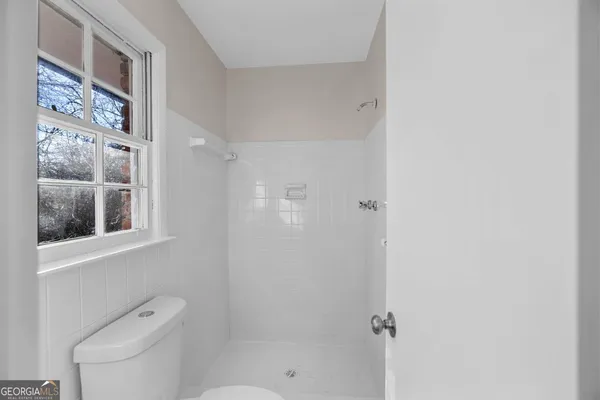 a bathroom with a shower a toilet and a window