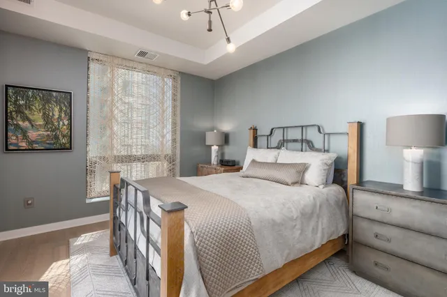 a bedroom with a bed a chandelier and a dresser