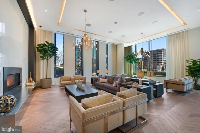 a living room with couches and kitchen view with wooden floor