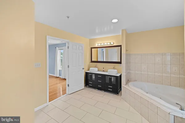 a view of a hallway with wooden floor and a bathroom