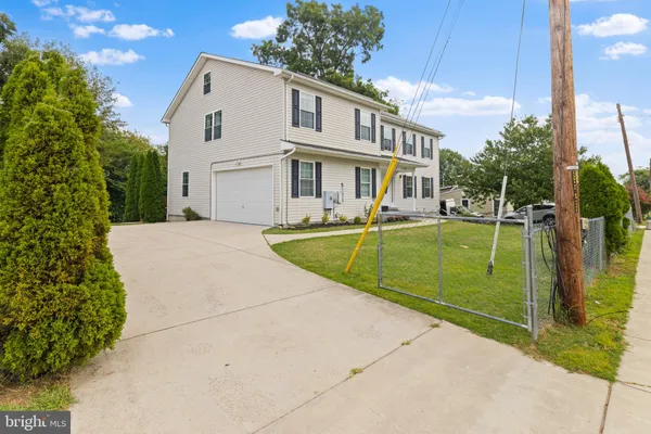 a view of a white house with a big yard and potted plants