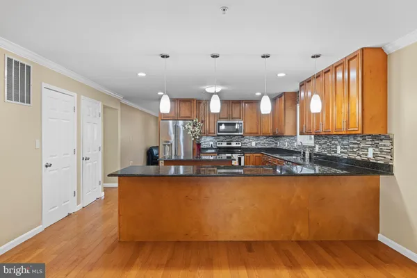 a large kitchen with stainless steel appliances granite countertop a granite counter tops and a wooden floors