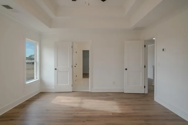 a view of an empty room with wooden floor and window
