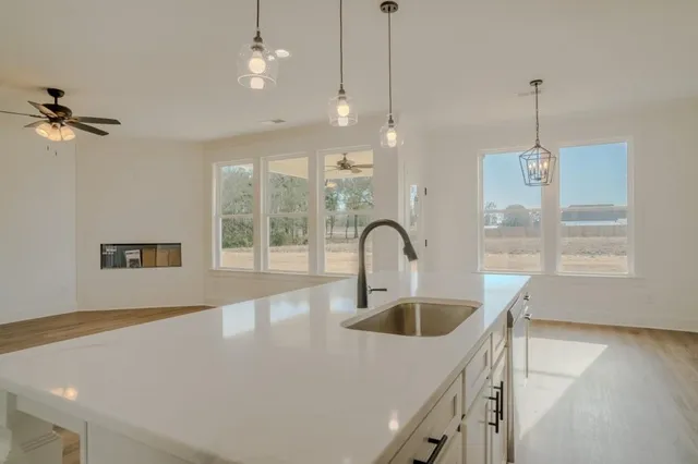 a kitchen with a sink a faucet a chandelier and living room view