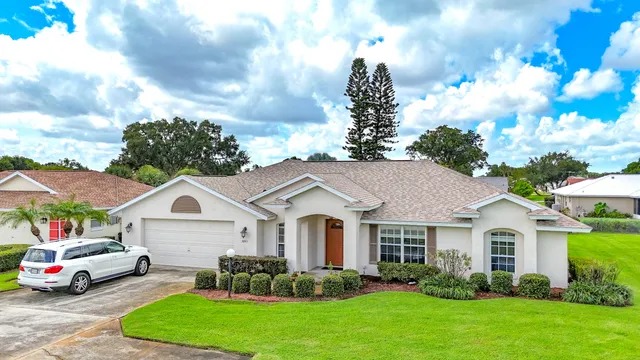 a white house with a big yard and potted plants