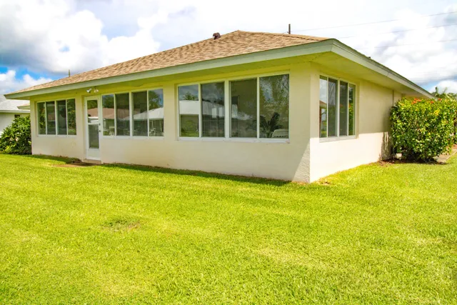 a view of a white house with a large window and garden