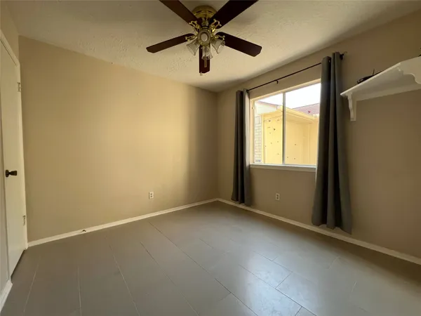 an empty room with a window and a ceiling fan