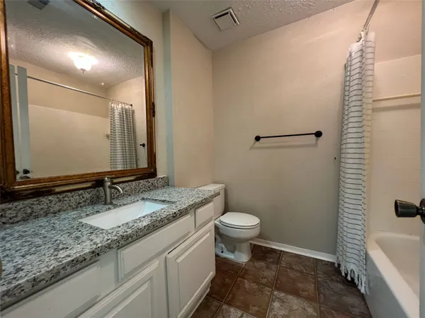 a bathroom with a granite countertop sink toilet and mirror