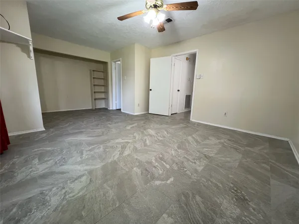 an empty room with chandelier fan and closet area