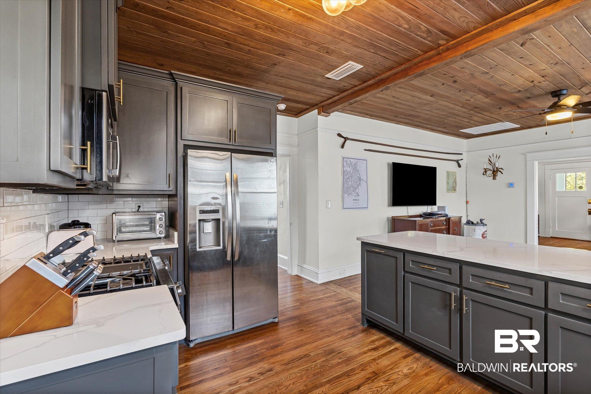 11 South Lafayette Street Mobile, AL 36604 - Photo 9 of 20 Kitchen with light stone countertops, stainless steel appliances, gray cabinets, dark wood-type flooring, and a wooden ceiling with exposed beams