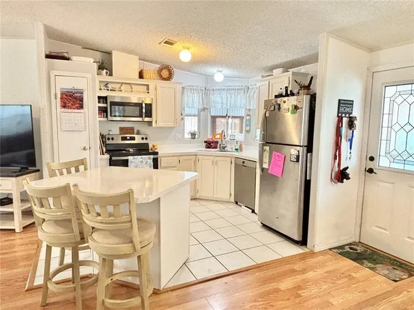 a kitchen with stainless steel appliances kitchen island granite countertop a refrigerator and microwave