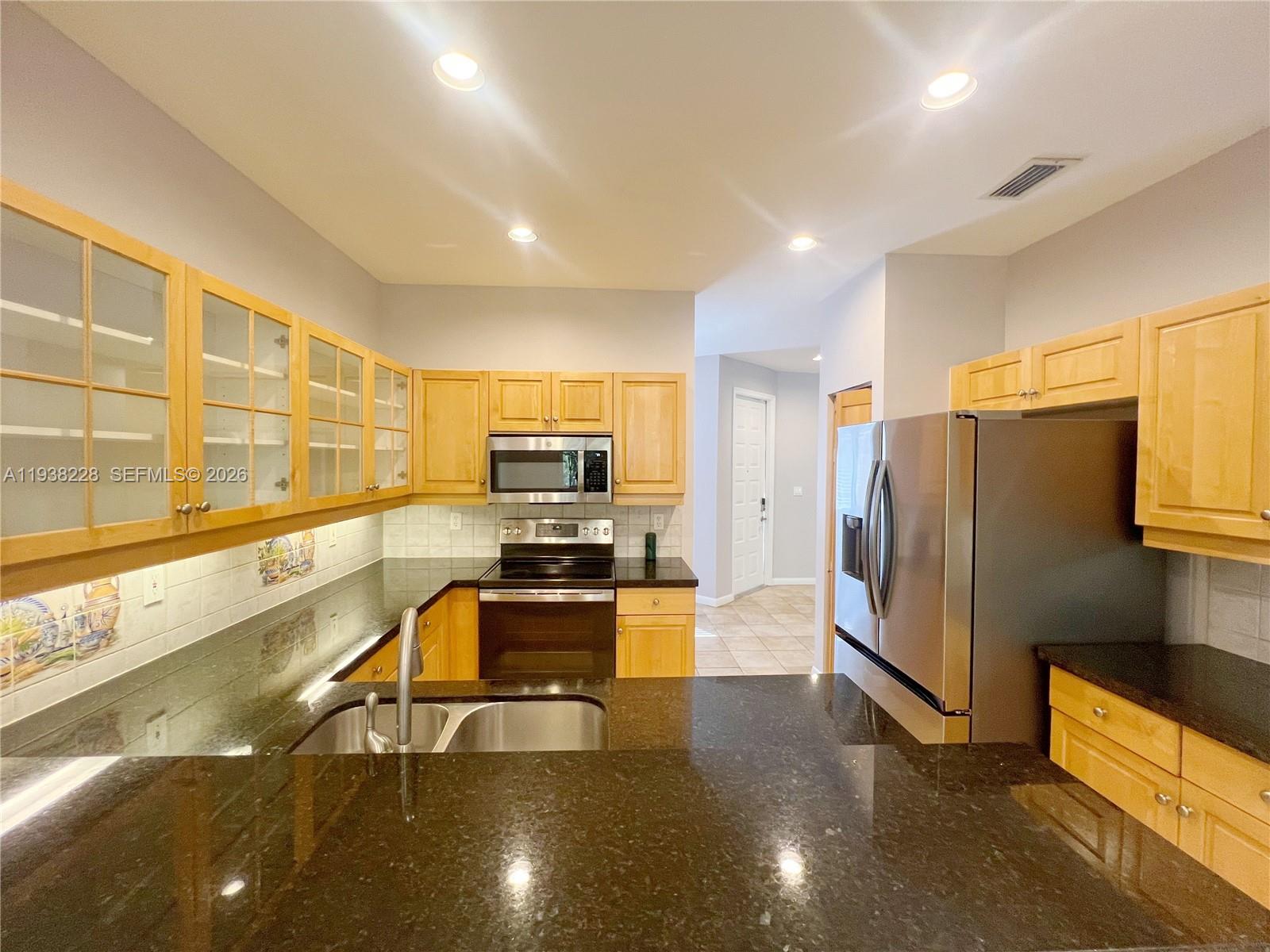 15827 Southwest 12th Street Pembroke Pines, FL 33027 - Photo 8 of 24 a kitchen with stainless steel appliances a refrigerator a stove a sink a oven with wooden cabinets and floor