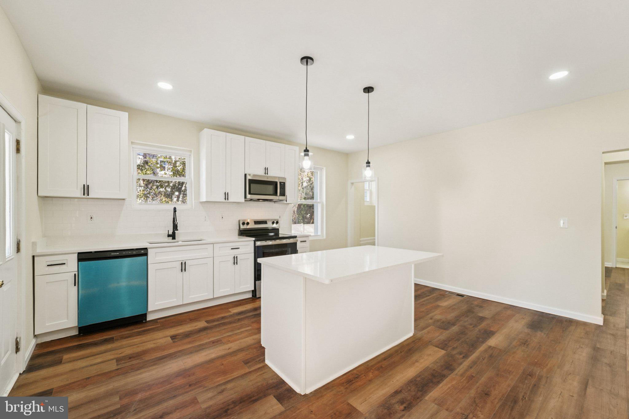 3603 Springdale Avenue Baltimore, MD 21216 - Photo 16 of 63 a kitchen with stainless steel appliances a stove top oven a sink dishwasher and a refrigerator with wooden floor