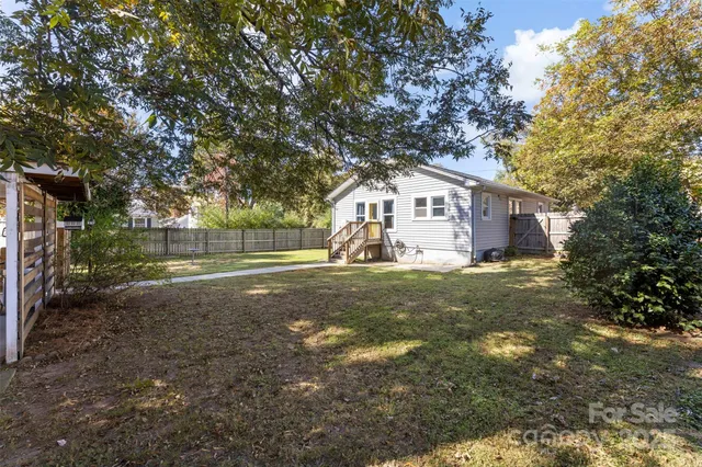 a view of a white house next to a yard with a big yard and large trees