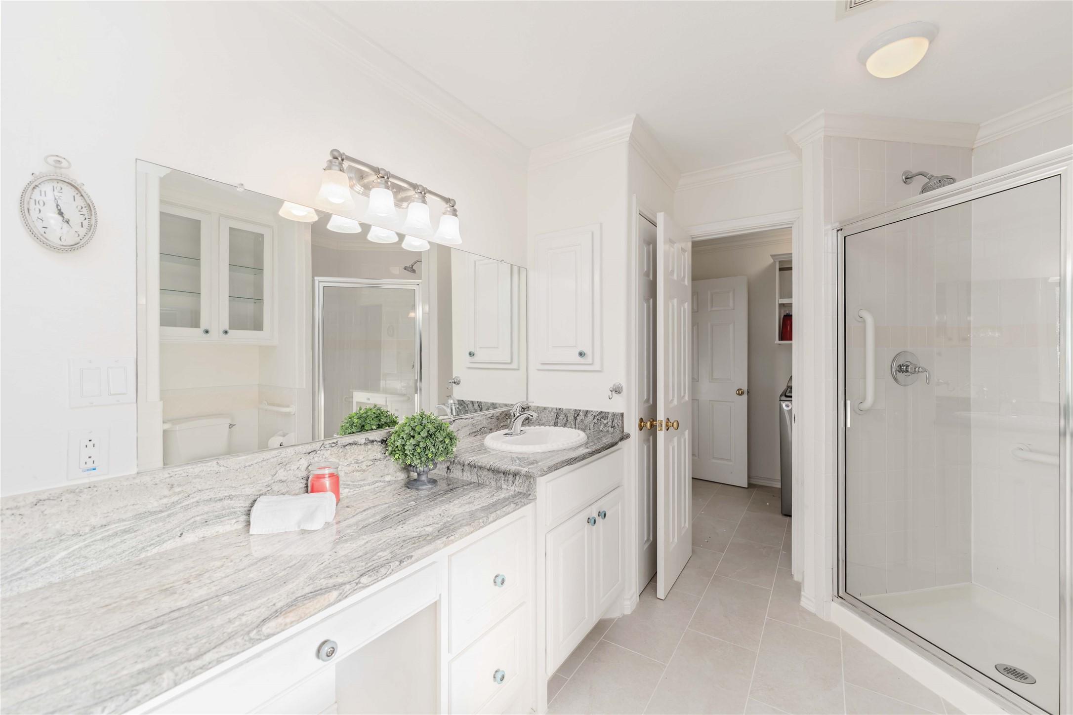 606 Packer Court Webster, TX 77598 - Photo 18 of 28 This bright bathroom features a spacious walk-in shower, elegant granite countertop with a single sink, ample cabinet storage, and moder lighting fixtures, creating a welcoming and functional space.