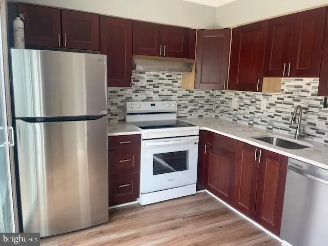 a white refrigerator freezer sitting inside of a kitchen with stainless steel appliances granite countertop wooden cabinets and a refrigerator