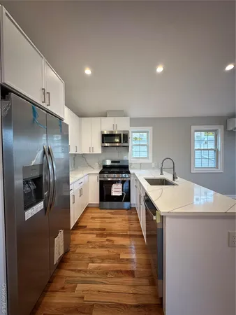 a large kitchen with stainless steel appliances granite countertop a sink a stove and a refrigerator