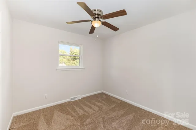 an empty room with a window and a fan