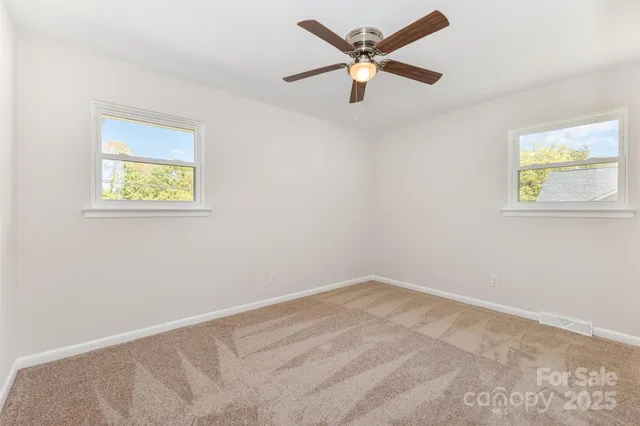 an empty room with a window and a fan