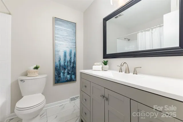 a bathroom with a granite countertop toilet sink and mirror