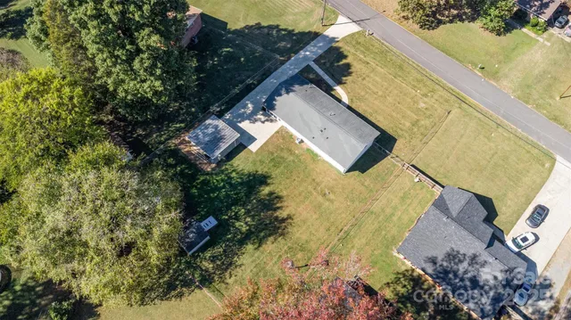 an aerial view of a house with swimming pool and large trees