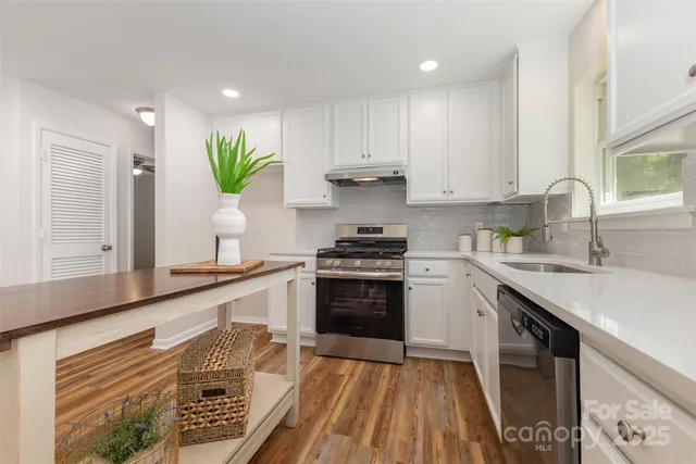 a kitchen with kitchen island granite countertop a sink cabinets stainless steel appliances and a counter top space