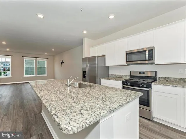 a kitchen with kitchen island granite countertop wooden cabinets and a refrigerator