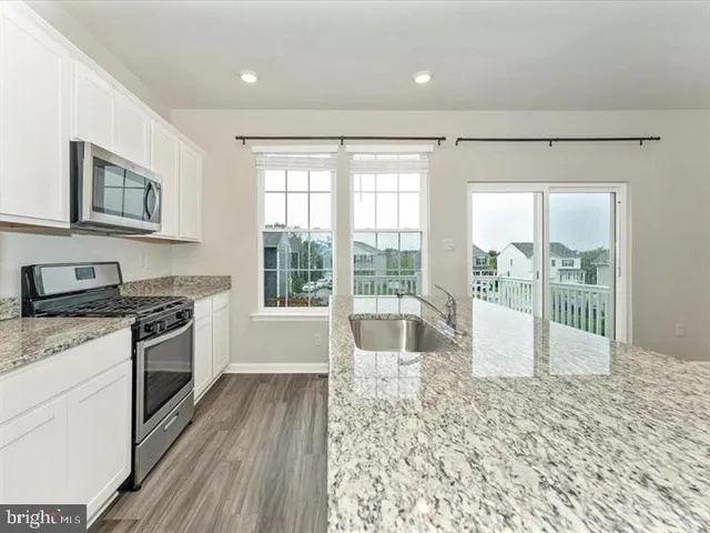 a large kitchen with granite countertop a stove a sink and a granite countertops with cabinets