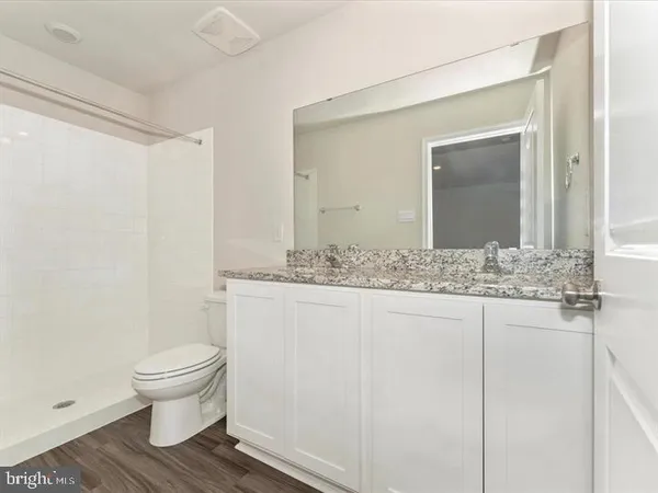 a bathroom with a granite countertop sink toilet and mirror