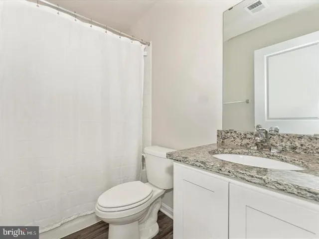 a bathroom with a granite countertop toilet and a sink