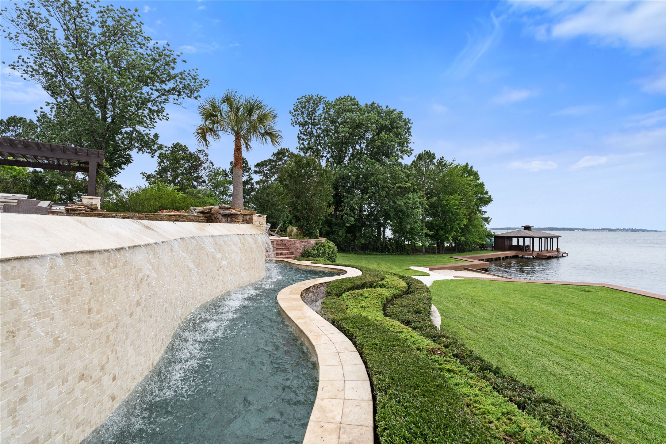 12349 Longmire Trace Conroe, TX 77304 - Photo 40 of 48 Infinity-edge pool spillway leads to manicured lawn, private dock, and sweeping lake views.
