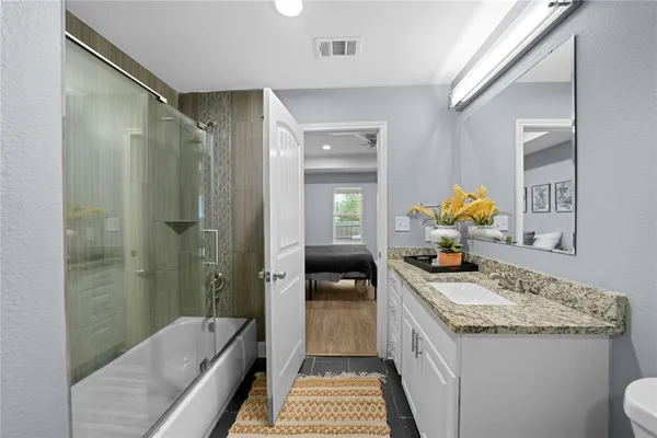 a bathroom with a granite countertop sink a toilet and shower
