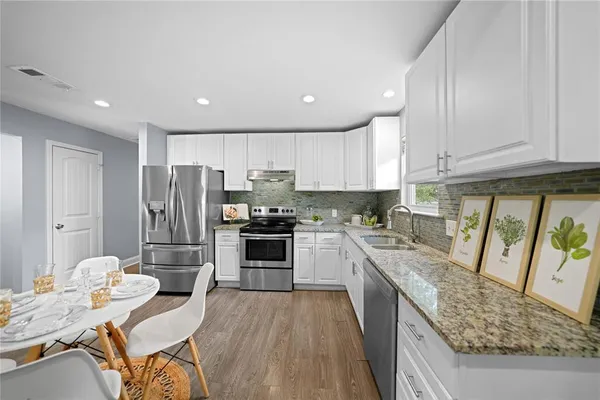 a kitchen with stainless steel appliances granite countertop a refrigerator stove microwave and sink